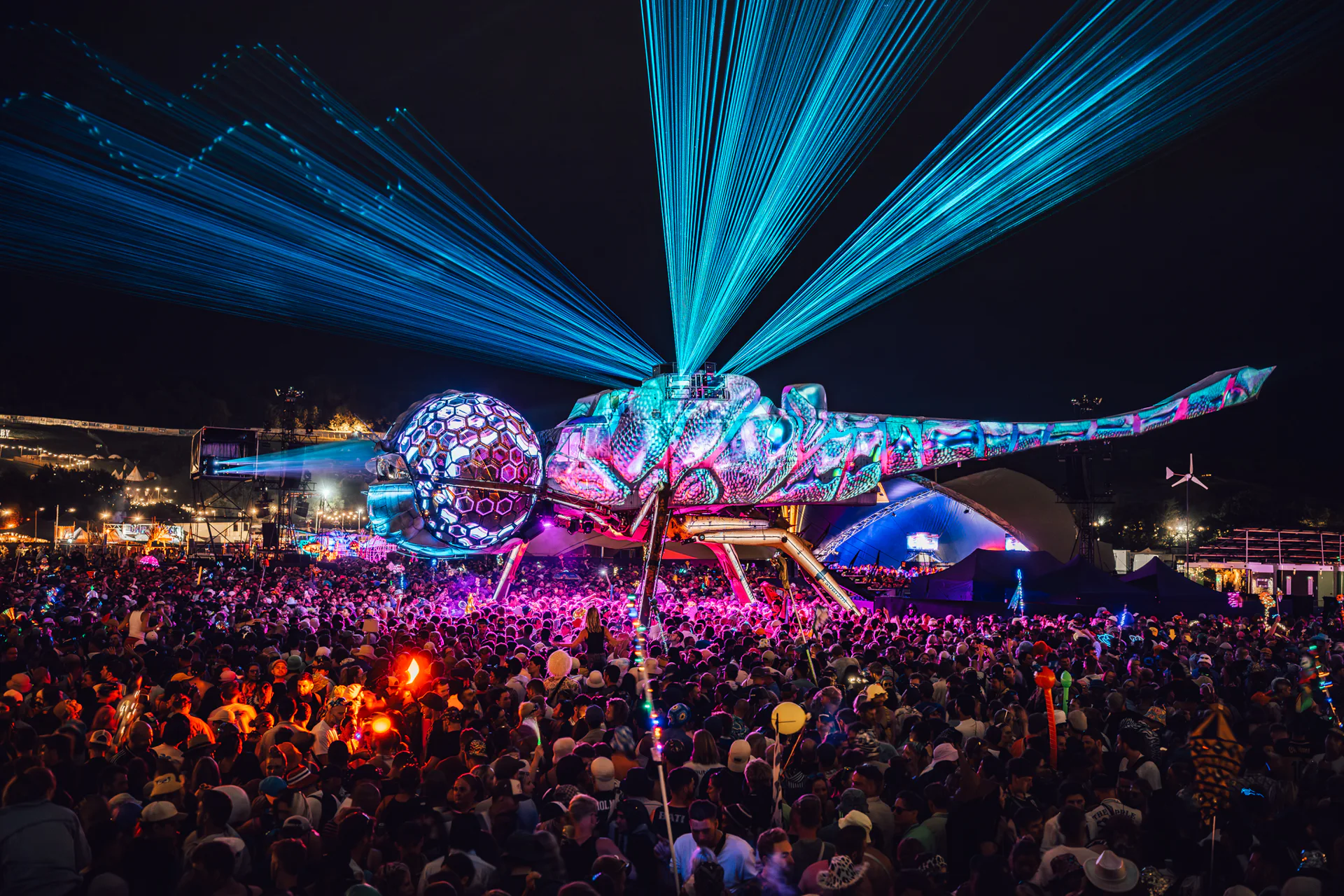Blue laser beams above the illuminated Dragonfly installation and crowd at Glastonbury Festival